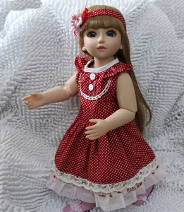 Detail of cute BJD doll with brown hair and polka dot dress on soft white carpet