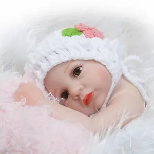 Poupée bébé reborn réaliste avec bonnet blanc à fleurs enveloppée dans une couverture rose