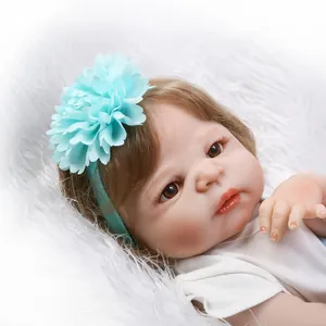 Lifelike reborn baby doll with brown hair and blue flower headband on white faux fur