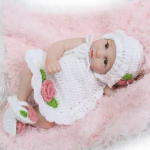 Poupée nouveau-né avec ensemble en tricot blanc et fleurs roses sur fond en peluche