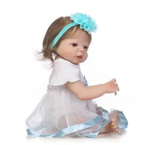 Detail of reborn baby doll with brown hair, blue floral headband, and white tutu dress