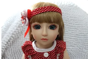 Close-up of cute BJD doll face with blonde hair, blue eyes and red polka dot headband