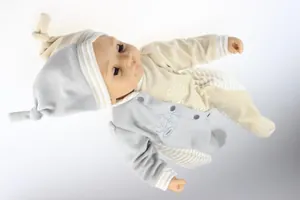Detailed view of lifelike baby doll wearing a soft striped beige and grey romper