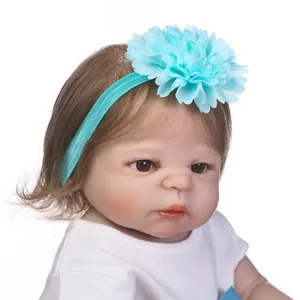 Realistic baby doll wearing a light blue layered fabric flower headband with elastic band