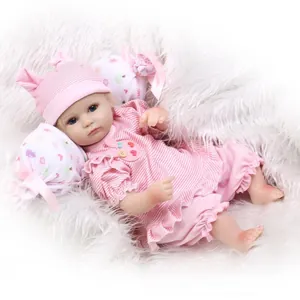 Muñeca bebé reborn realista con traje de rayas rosas sobre alfombra de felpa blanca