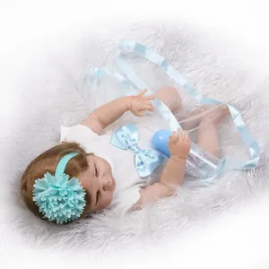 Realistic sleeping baby doll with blue flower headband and feeding bottle on plush rug