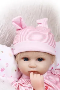 Primer plano de muñeca realista con ojos azules y gorro de punto a rayas rosa