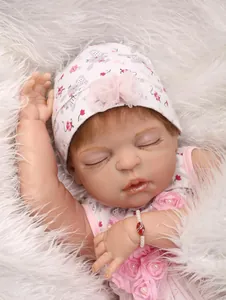 Primo piano di una bambola reborn che dorme con abito floreale e braccialetto di perle