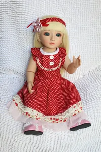 Detail of a BJD doll featuring blonde hair, blue eyes, and red polka dot dress on white fur