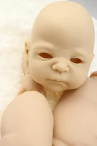 Macro shot of unpainted soft vinyl reborn doll kit components on white plush background