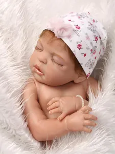 Dettaglio di una bambola realistica che dorme con cappello a fiori e braccialetto