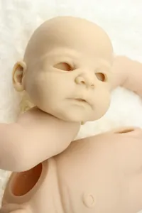 Detailed view of unpainted vinyl reborn doll kit parts on a white plush background