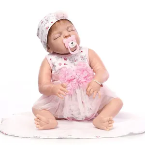 Dettaglio di una bambola reborn che dorme in abito floreale rosa con ciuccio e cappello