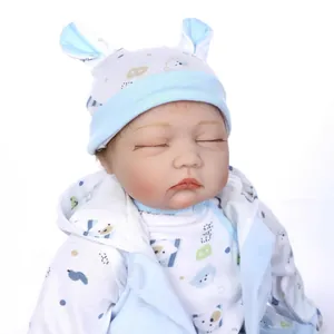 Realistic newborn reborn baby doll in blue bear outfit with closed eyes sleeping pose