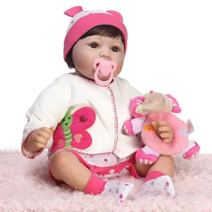 Lifelike reborn baby doll in pink floral outfit with plush elephant toy on soft rug
