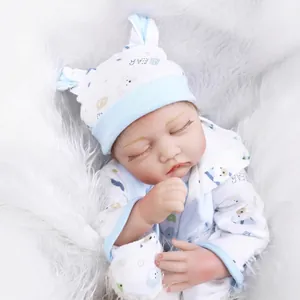 Lifelike sleeping reborn baby doll in a blue bear outfit on a white plush background