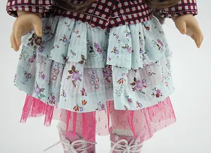 Detail of doll outfit featuring plaid shirt, floral pleated skirt and pink boots