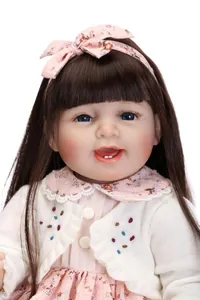 Close-up of a realistic smiling baby doll with brown hair and pink floral bow