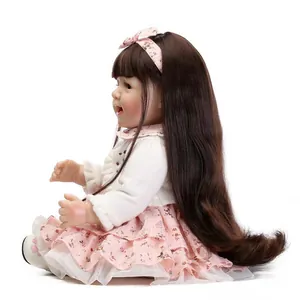 Realistic reborn doll with long brown hair, floral dress and white knitted cardigan