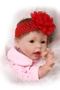 Close-up of realistic reborn baby doll with brown hair and red floral headband