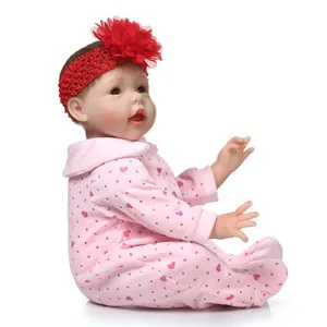 Realistic reborn baby doll in pink heart onesie and red flower headband on white background