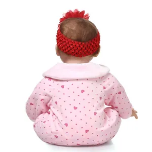 Realistic reborn baby doll back view wearing a pink heart onesie and red floral headband