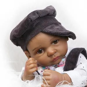 Close-up of realistic reborn black baby doll in grey corduroy outfit on plush background