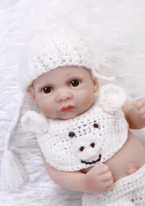 Close-up of realistic silicone baby doll with handmade white crochet hat and pig bib