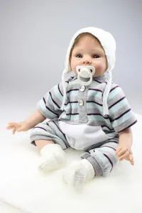 Close-up of lifelike reborn baby doll in striped romper with knit hat and pacifier