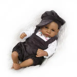 Close-up of realistic dark-skin baby doll wearing dark grey corduroy overalls and hat