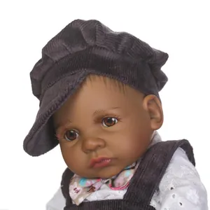 Close-up of a lifelike dark skin reborn baby doll wearing a brown corduroy hat and overalls