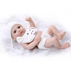 Lifelike soft silicone baby doll in white bear knit outfit on white faux fur carpet