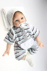 Macro detail of lifelike reborn doll wearing striped outfit and knit hat on white blanket