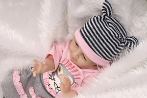 Gros plan d'une poupée reborn réaliste avec haut floral rose et bonnet à oreilles