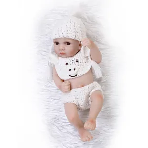 Realistic silicone baby doll in white knit lamb outfit on a soft plush background