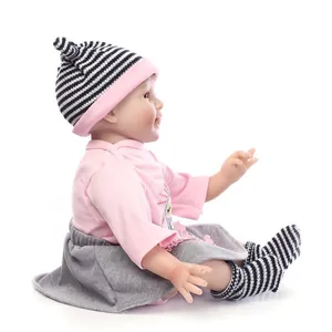 Détail de la poupée réaliste avec haut rose, jupe grise et bonnet en tricot doux
