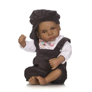 Detail of realistic black baby doll wearing a white embroidered shirt and corduroy outfit