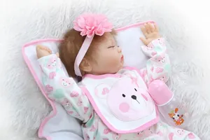 Detailed close-up of a realistic reborn sleeping baby doll with pink accessories and bottle