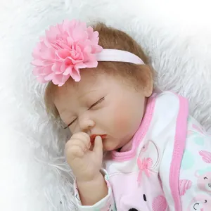 Lifelike reborn baby doll in pink floral headband sleeping on soft white plush rug