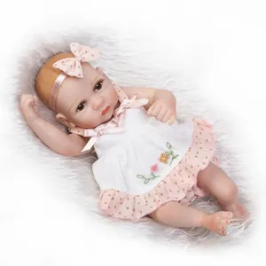 Close-up of realistic newborn baby doll with pink polka dot headband and floral embroidery