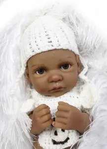 Close-up of African reborn doll with white knitted hat and smiley face outfit