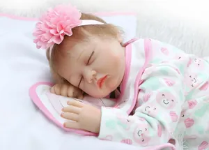 Close-up of lifelike sleeping reborn baby doll with pink flower headband and printed romper