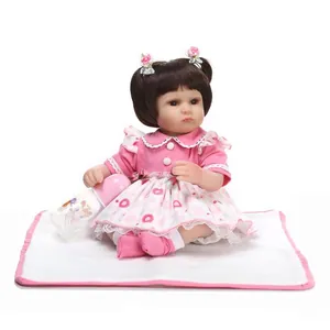 Realistic reborn baby doll with brown pigtails wearing a floral lace pink dress