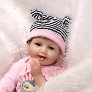 Poupée bébé Reborn réaliste en barboteuse rose et bonnet rayé sur fond en peluche