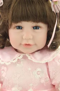 Macro detail of reborn doll with blue eyes, brown curls, and pink lace embroidery dress