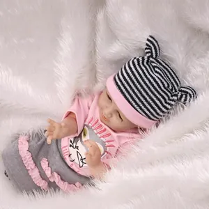 Poupée bébé reborn réaliste avec tenue rose et bonnet rayé sur tapis en peluche
