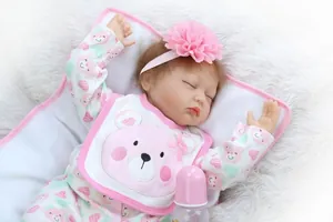 Close-up of realistic reborn baby doll in pink bear outfit with large flower headband