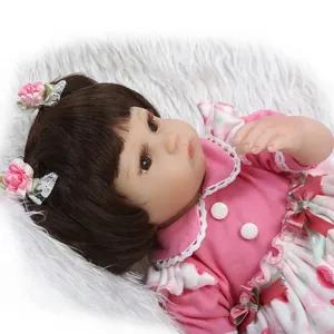 Close-up of lifelike baby doll with brown hair, floral hair clips, and pink polka dot dress
