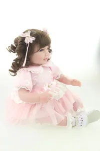 Detailed close-up of 20-inch reborn doll with curly brown hair and pink lace dress