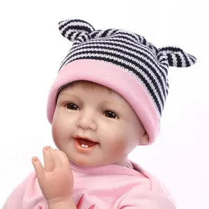 Poupée bébé reborn réaliste avec visage souriant et chapeau rose sur fond blanc